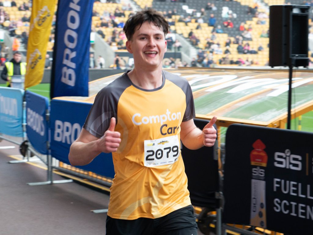 A runner in a Compton top cheers as he crosses the finish line